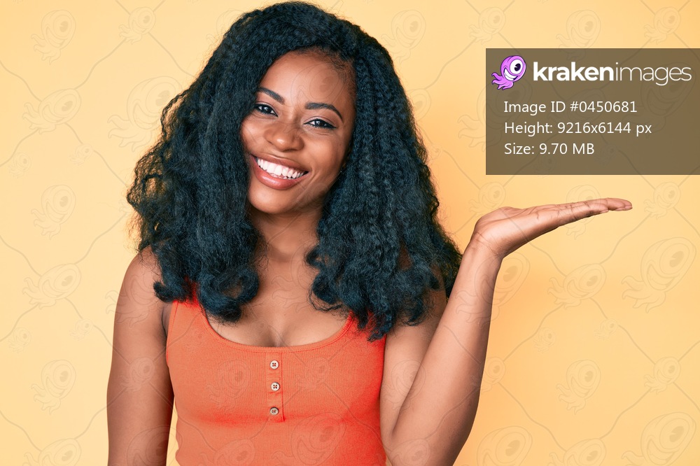 Beautiful african woman wearing casual clothes smiling cheerful presenting and pointing with palm of hand looking at the camera. 