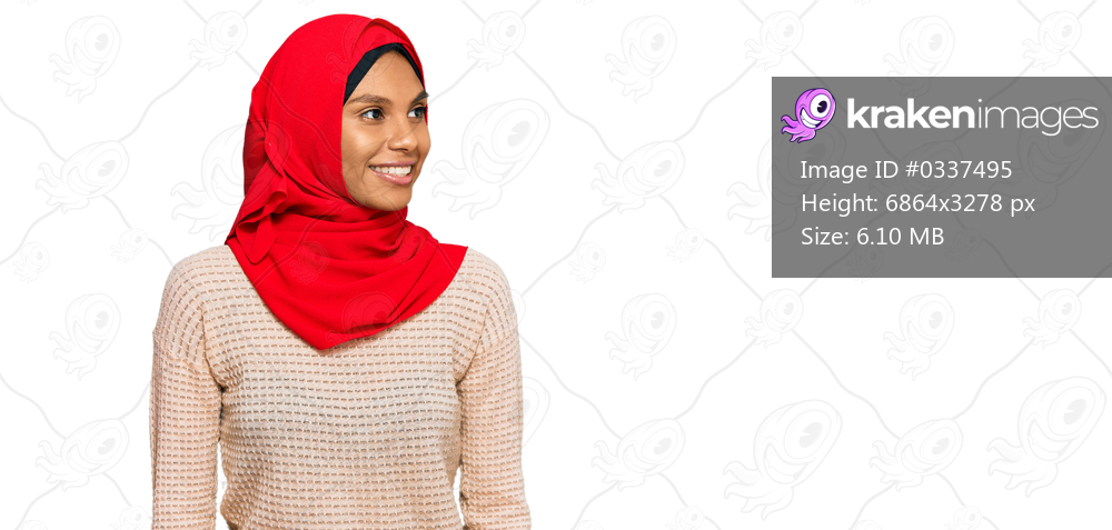 Young african american woman wearing traditional islamic hijab scarf looking away to side with smile on face, natural expression. laughing confident. 