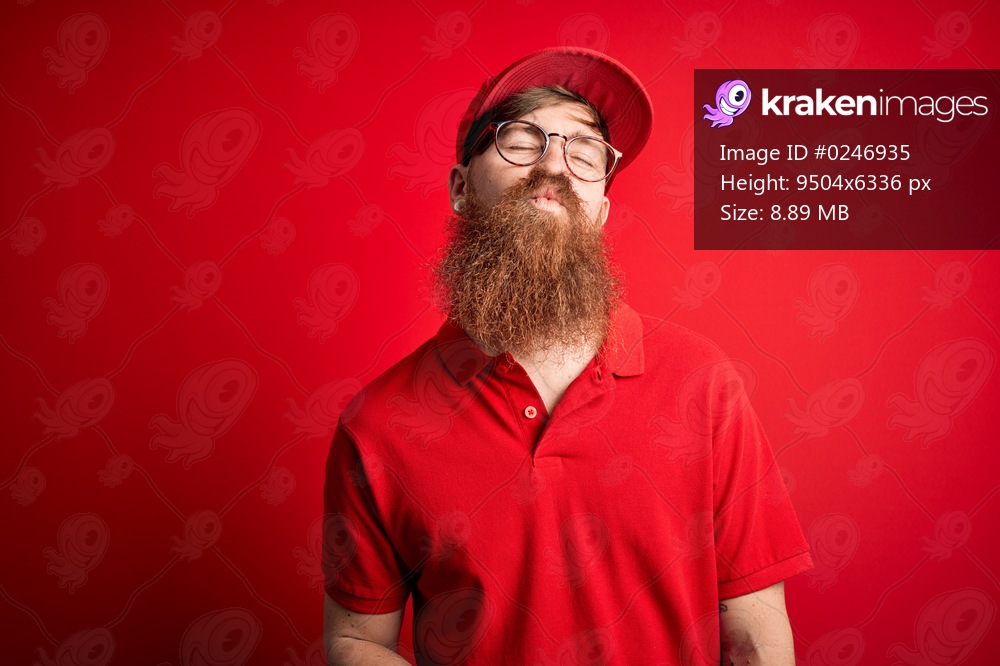 Young handsome delivery man wearing glasses and red cap over isolated background looking at the camera blowing a kiss on air being lovely and sexy. Love expression.