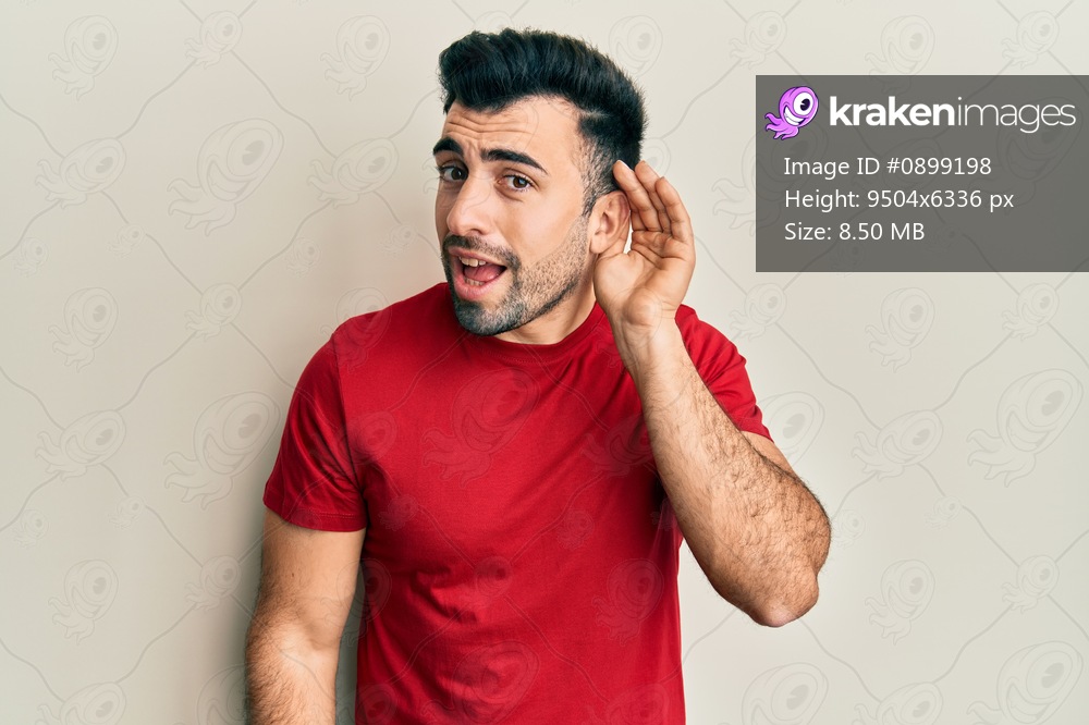 Young hispanic man wearing casual clothes smiling with hand over ear listening and hearing to rumor or gossip. deafness concept. 