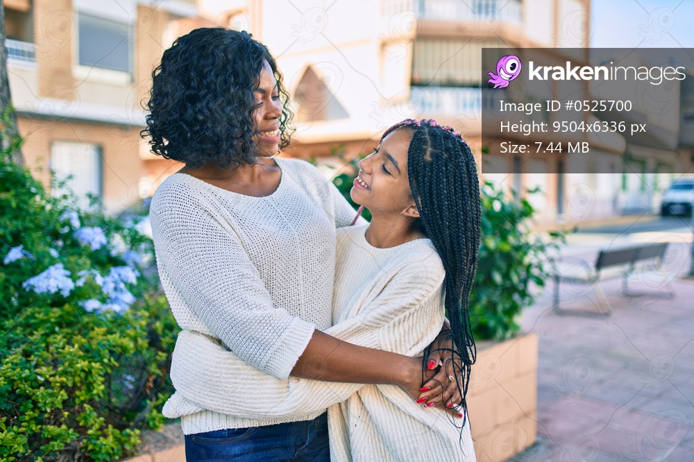 Beautiful african american mother and daughter smiling happy and hugging. Standing with smile on face standing at the park