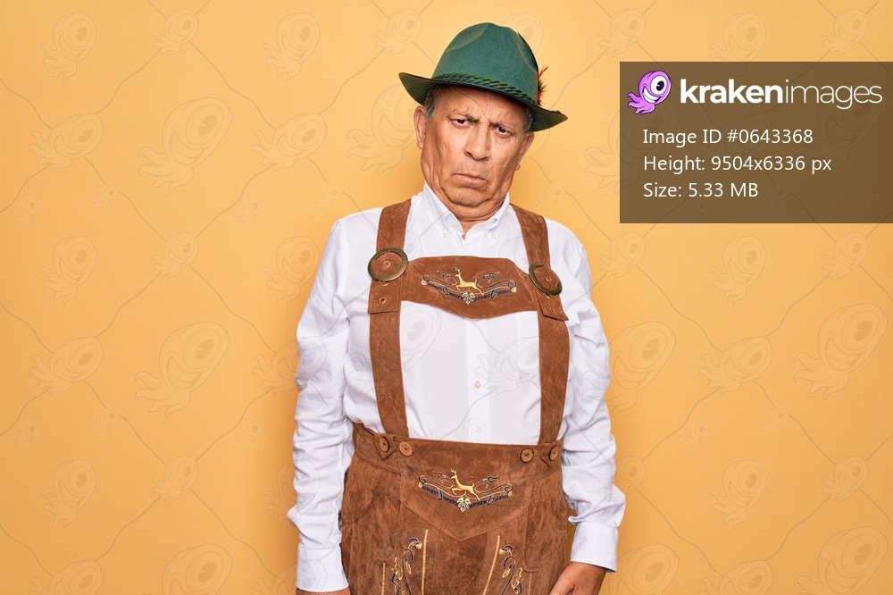 Senior grey-haired man wearing german traditional octoberfest suit over yellow background skeptic and nervous, frowning upset because of problem. Negative person.
