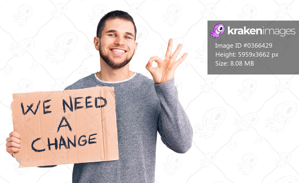 Young handsome man holding we need a change banner doing ok sign with fingers, smiling friendly gesturing excellent symbol 