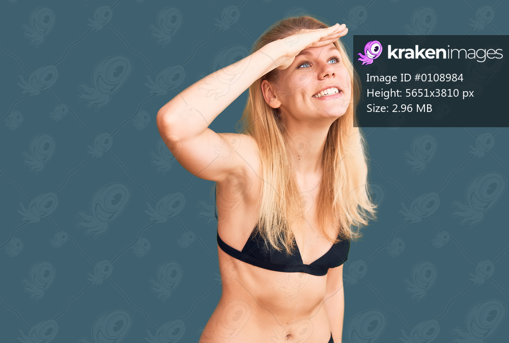 Young beautiful blonde woman wearing bikini very happy and smiling looking far away with hand over head. searching concept. 