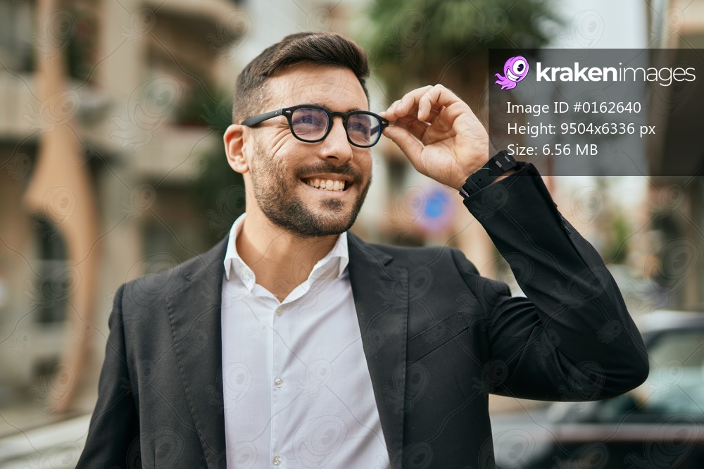 Young hispanic businessman smiling happy standing at the city.