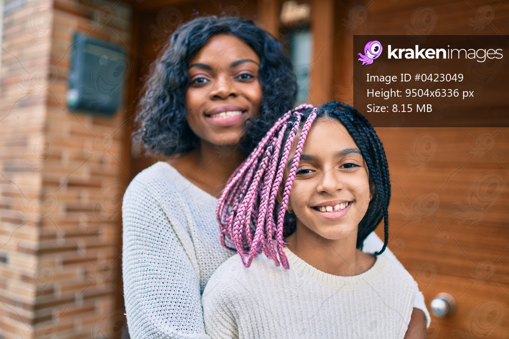 Beautiful african american mother and daughter smiling happy and hugging. Standing with smile on face standing at the city.
