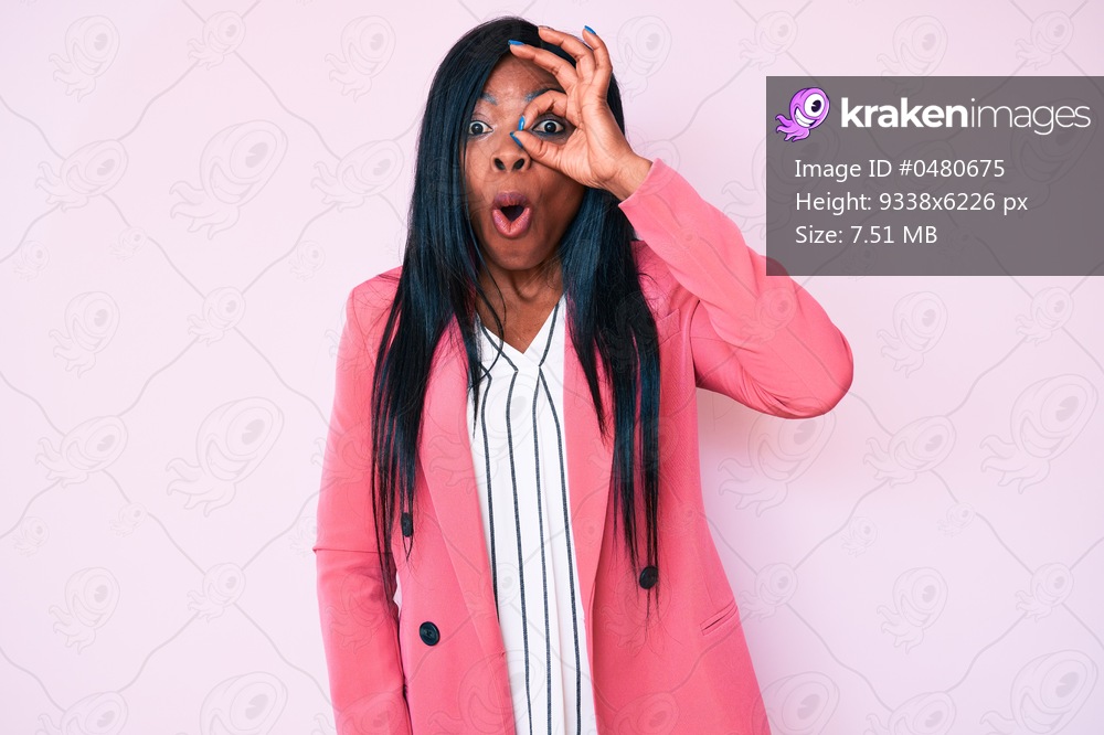 Young african american woman wearing business clothes doing ok gesture shocked with surprised face, eye looking through fingers. unbelieving expression. 