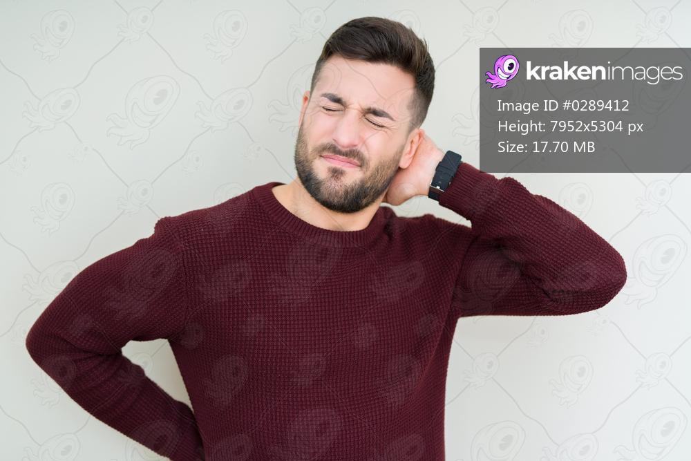 Young handsome man wearing a sweater over isolated background Suffering of neck ache injury, touching neck with hand, muscular pain