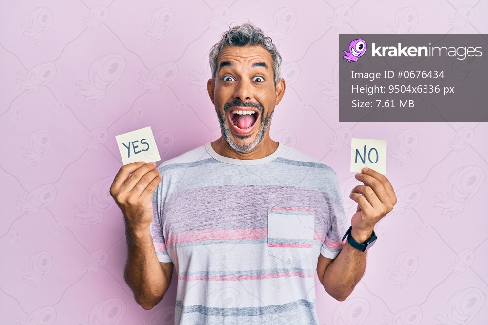 Middle age grey-haired man holding yes and no reminder celebrating crazy and amazed for success with open eyes screaming excited. 