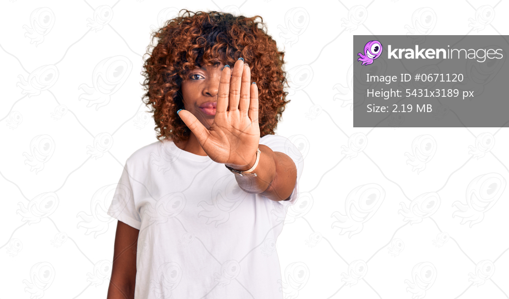 Young african american woman wearing casual white tshirt doing stop sing with palm of the hand. warning expression with negative and serious gesture on the face. 
