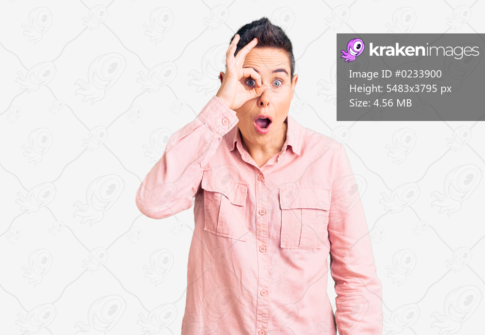 Young woman with short hair wearing casual clothes doing ok gesture shocked with surprised face, eye looking through fingers. unbelieving expression. 