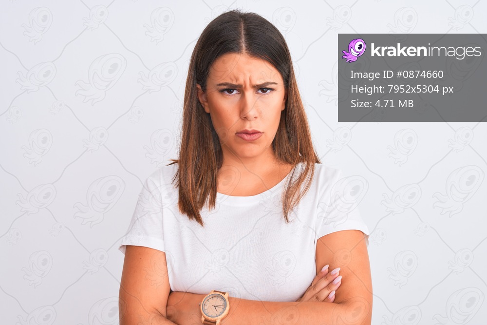 Portrait of beautiful and young brunette woman standing over isolated white background skeptic and nervous, disapproving expression on face with crossed arms. Negative person.