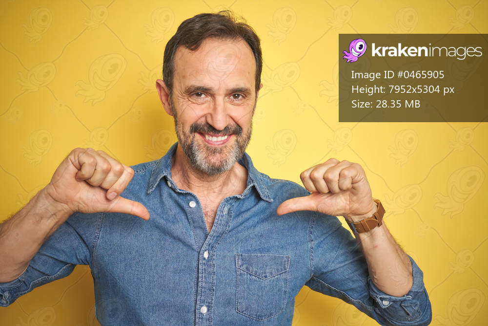 Handsome middle age senior man with grey hair over isolated yellow background looking confident with smile on face, pointing oneself with fingers proud and happy.