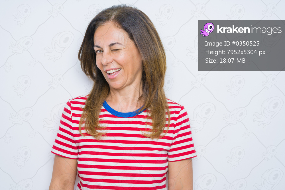 Middle age senior woman standing over white isolated background winking looking at the camera with sexy expression, cheerful and happy face.