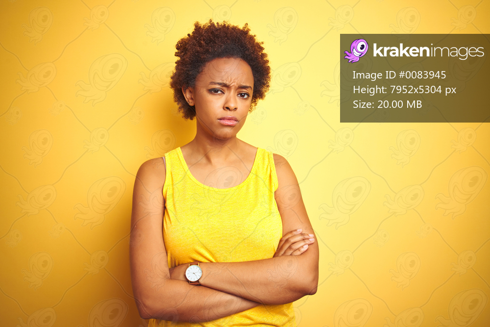 Beauitul african american woman wearing summer t-shirt over isolated yellow background skeptic and nervous, disapproving expression on face with crossed arms. Negative person.
