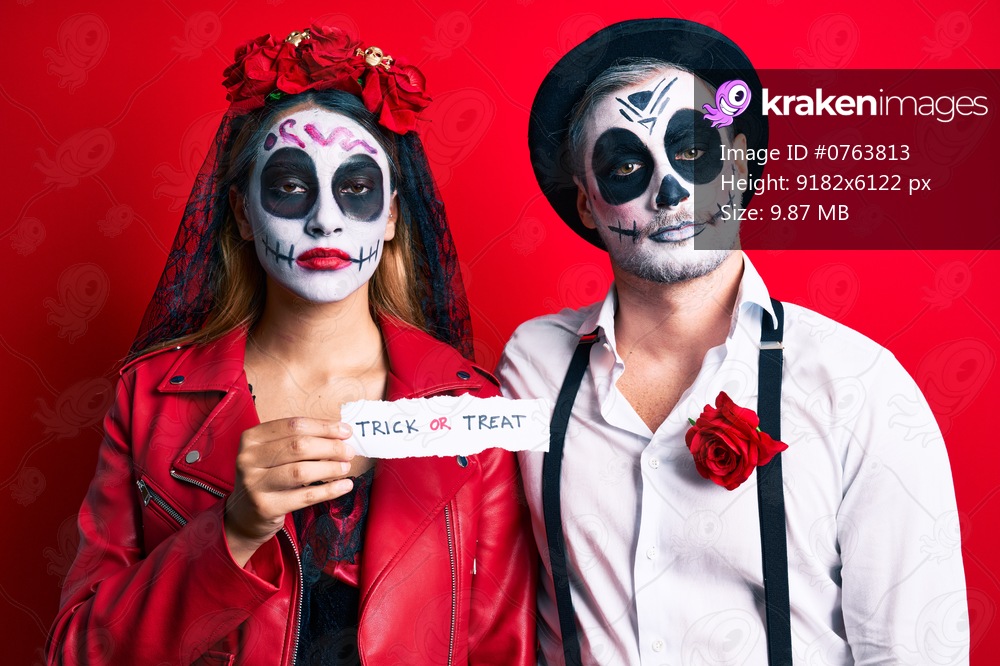 Couple wearing day of the dead costume holding trick or treat paper thinking attitude and sober expression looking self confident 