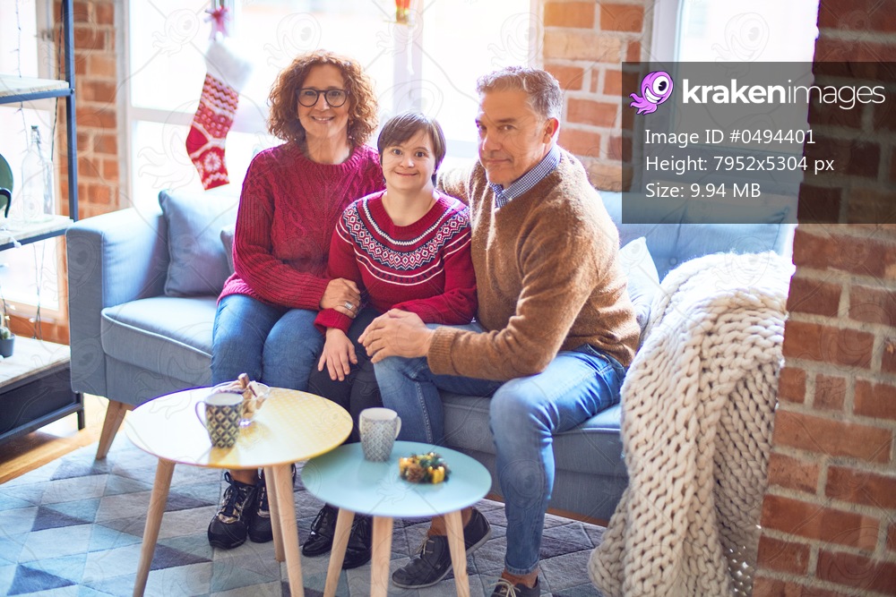 Beautiful family smiling happy and confident. Sitting on the sofa with smile on face hugging around christmas decorations at home