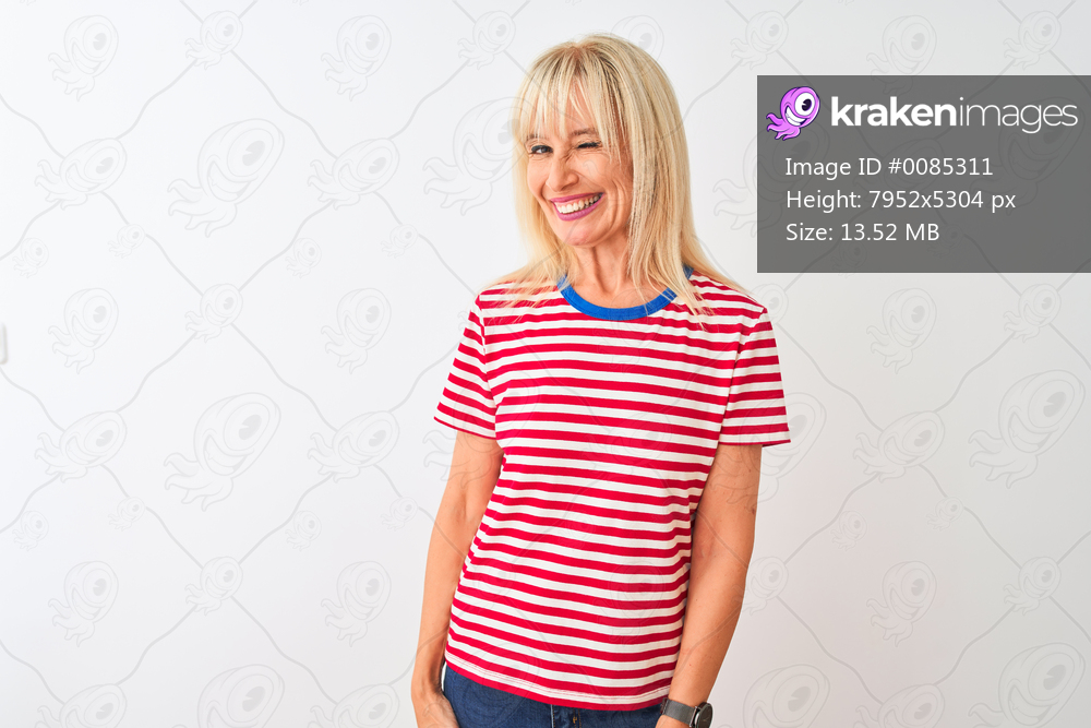 Middle age woman wearing casual striped t-shirt standing over isolated white background winking looking at the camera with sexy expression, cheerful and happy face.