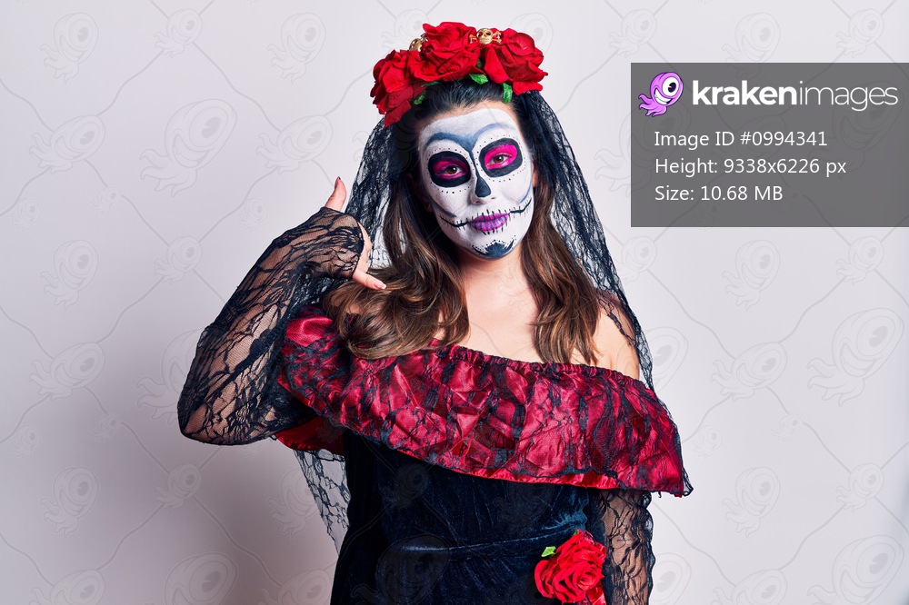 Young woman wearing day of the dead costume over white smiling doing phone gesture with hand and fingers like talking on the telephone. communicating concepts. 