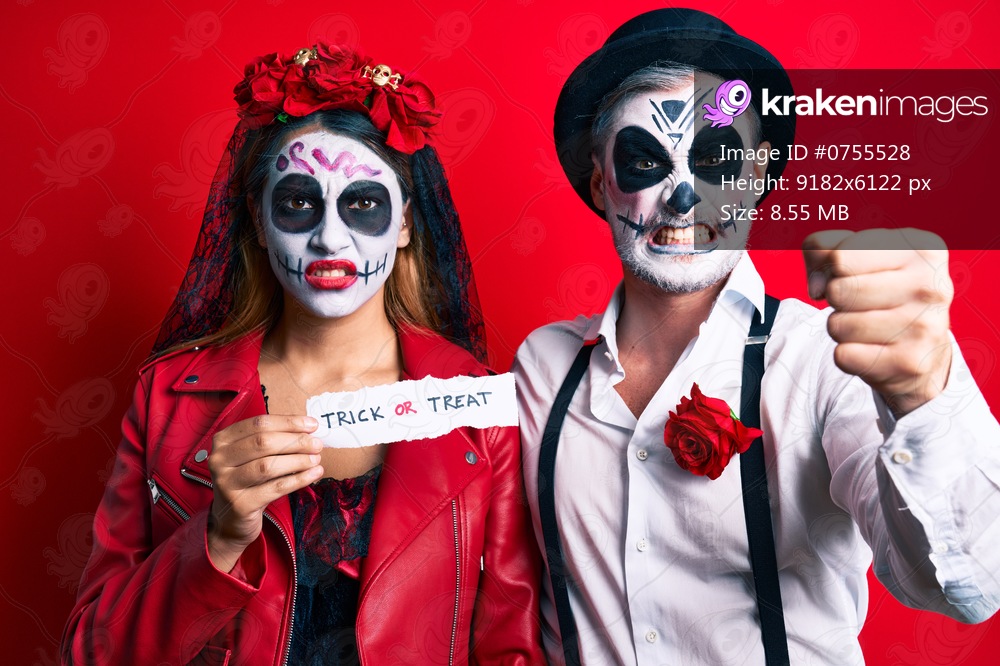 Couple wearing day of the dead costume holding trick or treat paper annoyed and frustrated shouting with anger, yelling crazy with anger and hand raised 