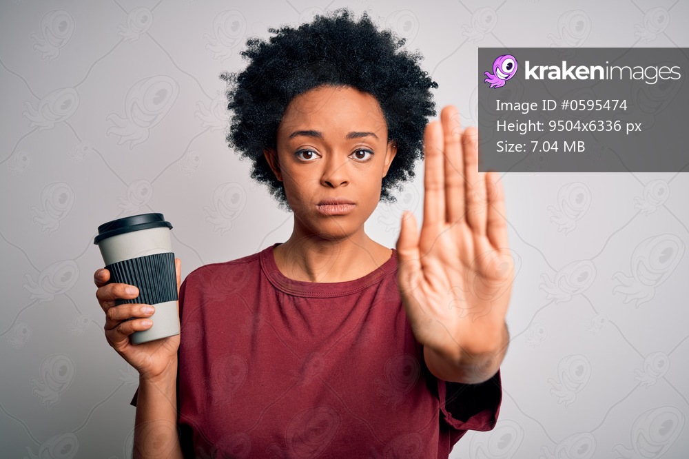Young African American afro woman with curly hair drinking cup of coffee with open hand doing stop sign with serious and confident expression, defense gesture