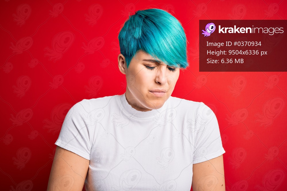 Young beautiful woman with blue fashion hair wearing casual t-shirt over red background with hand on stomach because indigestion, painful illness feeling unwell. Ache concept.