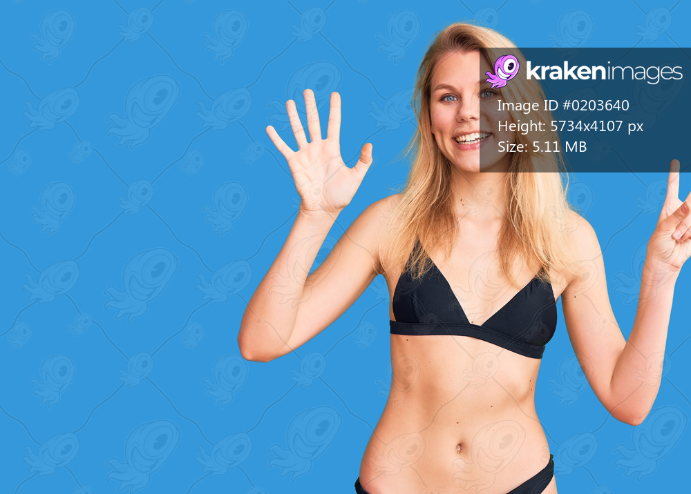 Young beautiful blonde woman wearing bikini showing and pointing up with fingers number seven while smiling confident and happy. 