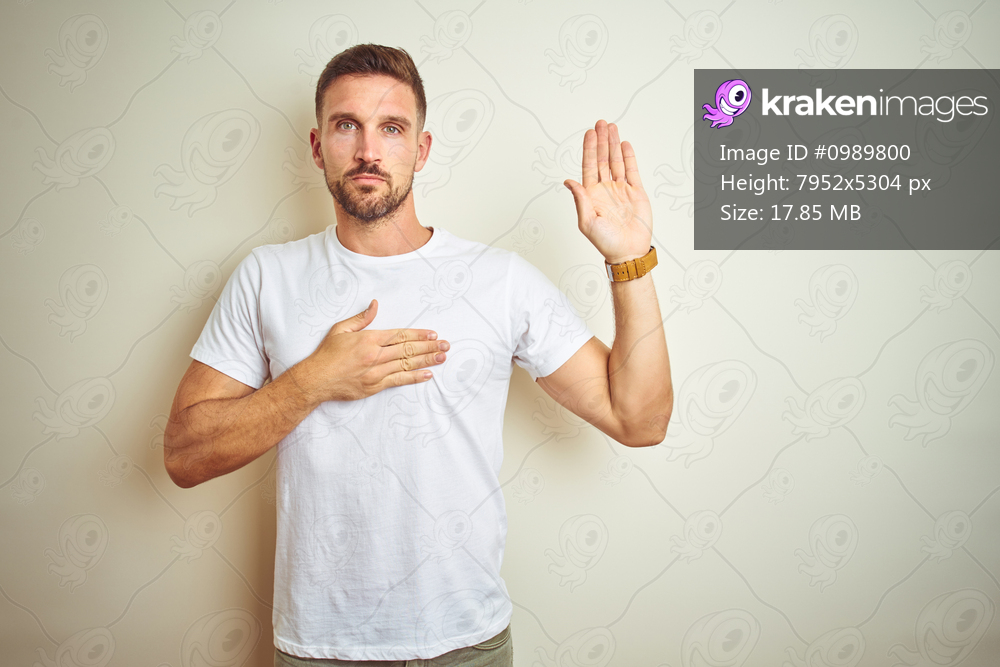 Young handsome man wearing casual white t-shirt over isolated background Swearing with hand on chest and open palm, making a loyalty promise oath