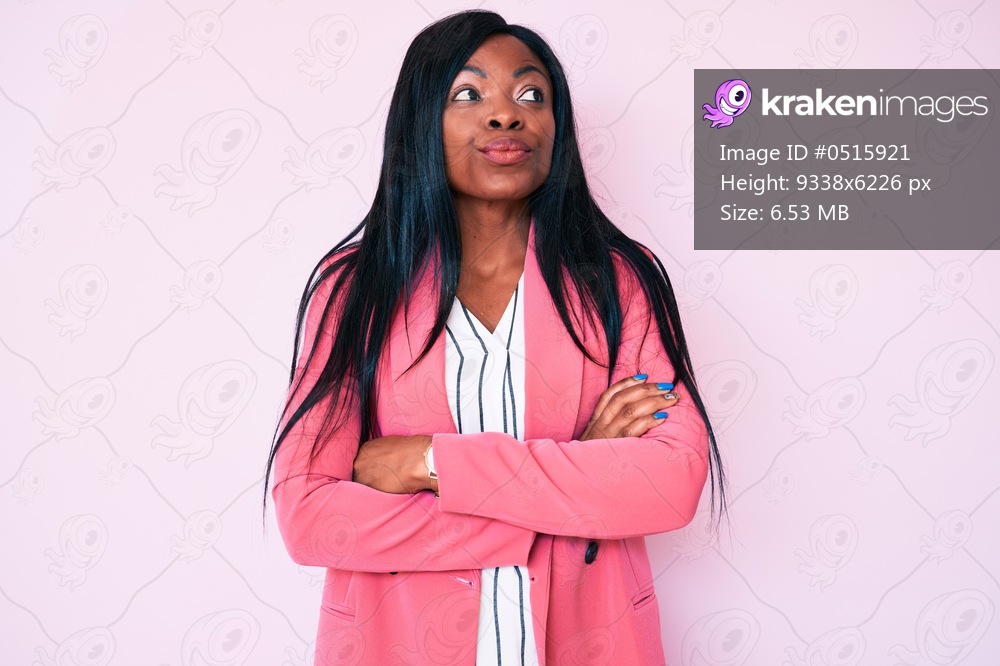 Young african american woman wearing business clothes smiling looking to the side and staring away thinking. 