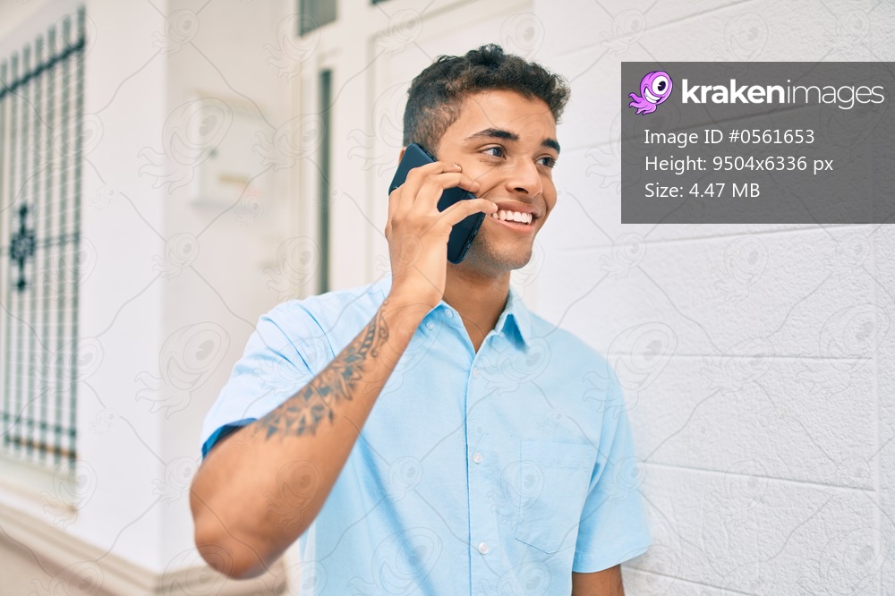 Young latin man smiling happy talking on the smartphone walking at the city.
