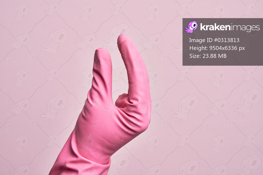 Hand of caucasian young man with cleaning glove over isolated pink background picking and taking invisible thing, holding object with fingers showing space