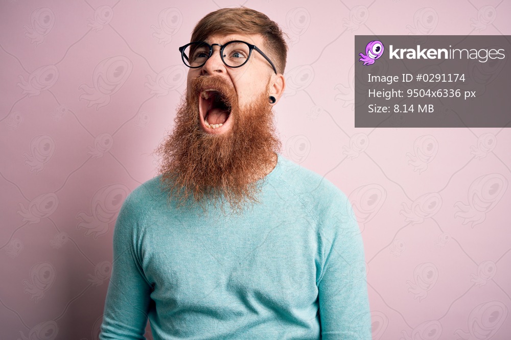 Handsome Irish redhead man with beard wearing glasses over pink isolated background angry and mad screaming frustrated and furious, shouting with anger. Rage and aggressive concept.