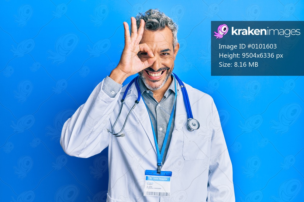 Middle age grey-haired man wearing doctor uniform and stethoscope doing ok gesture with hand smiling, eye looking through fingers with happy face. 