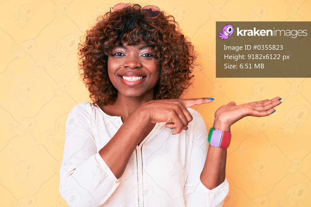 Young african american woman wearing casual clothes amazed and smiling to the camera while presenting with hand and pointing with finger. 