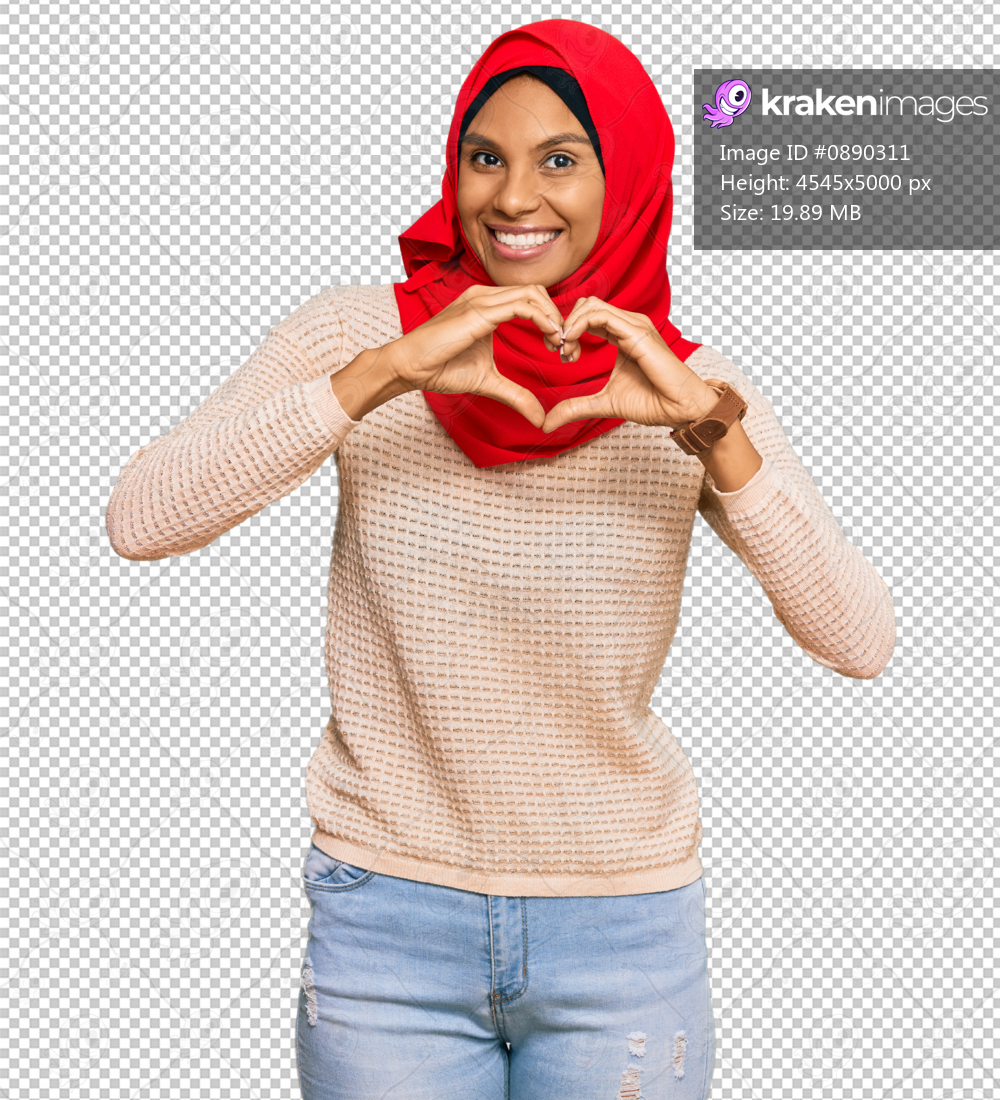 Young african american woman wearing traditional islamic hijab scarf smiling in love doing heart symbol shape with hands. romantic concept.