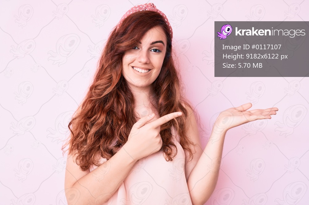 Young beautiful woman wearing casual clothes amazed and smiling to the camera while presenting with hand and pointing with finger. 