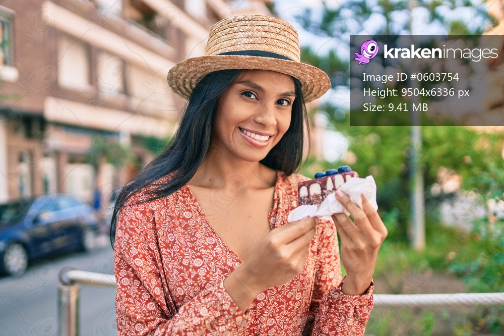 Young african american tourist woman on vacation eating cake at the city.