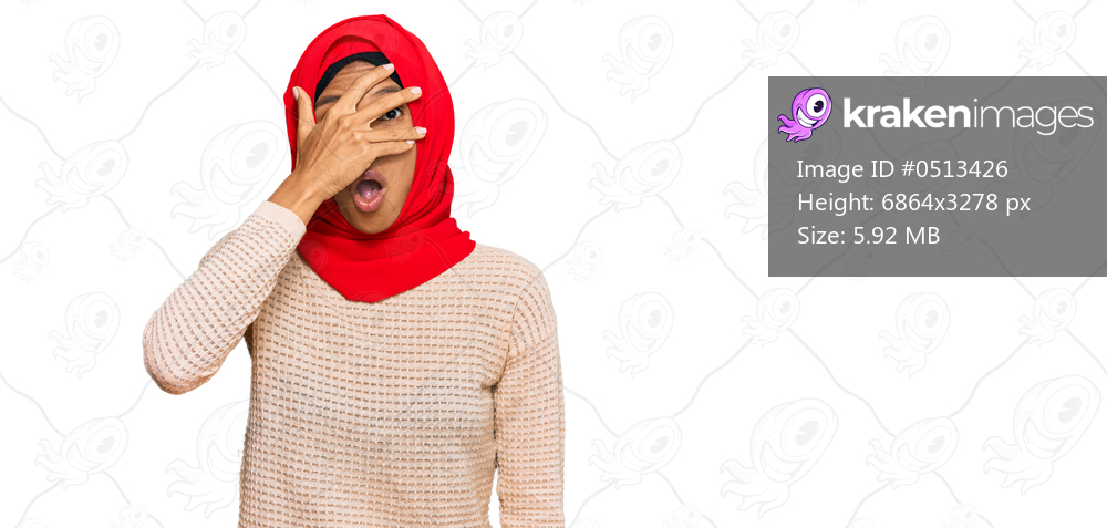 Young african american woman wearing traditional islamic hijab scarf peeking in shock covering face and eyes with hand, looking through fingers with embarrassed expression. 