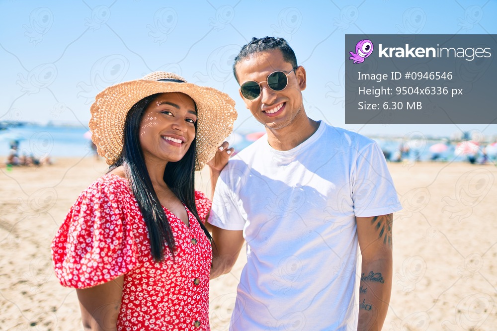 Young latin couple smiling happy and hugging at the beach.