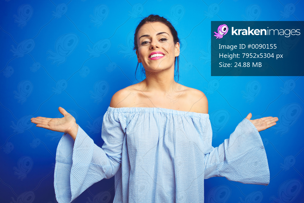 Young beautiful woman wearing bun hairstyle over blue isolated background smiling showing both hands open palms, presenting and advertising comparison and balance