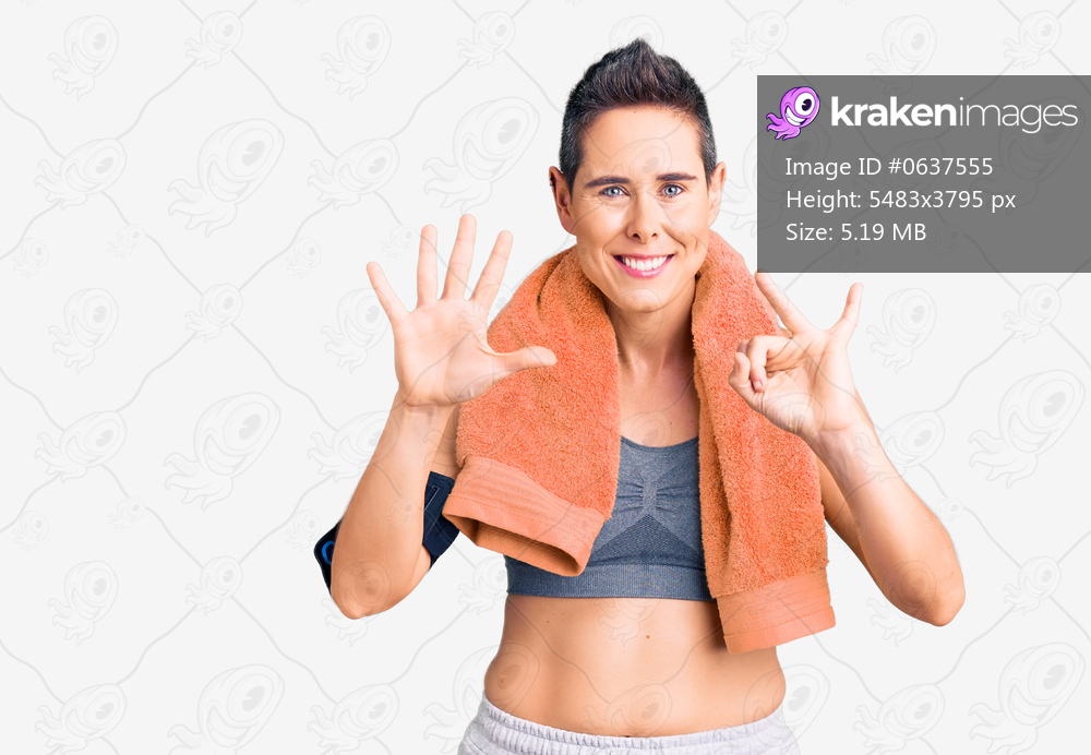 Young woman with short hair wearing sportswear and towel using smartphone showing and pointing up with fingers number seven while smiling confident and happy. 