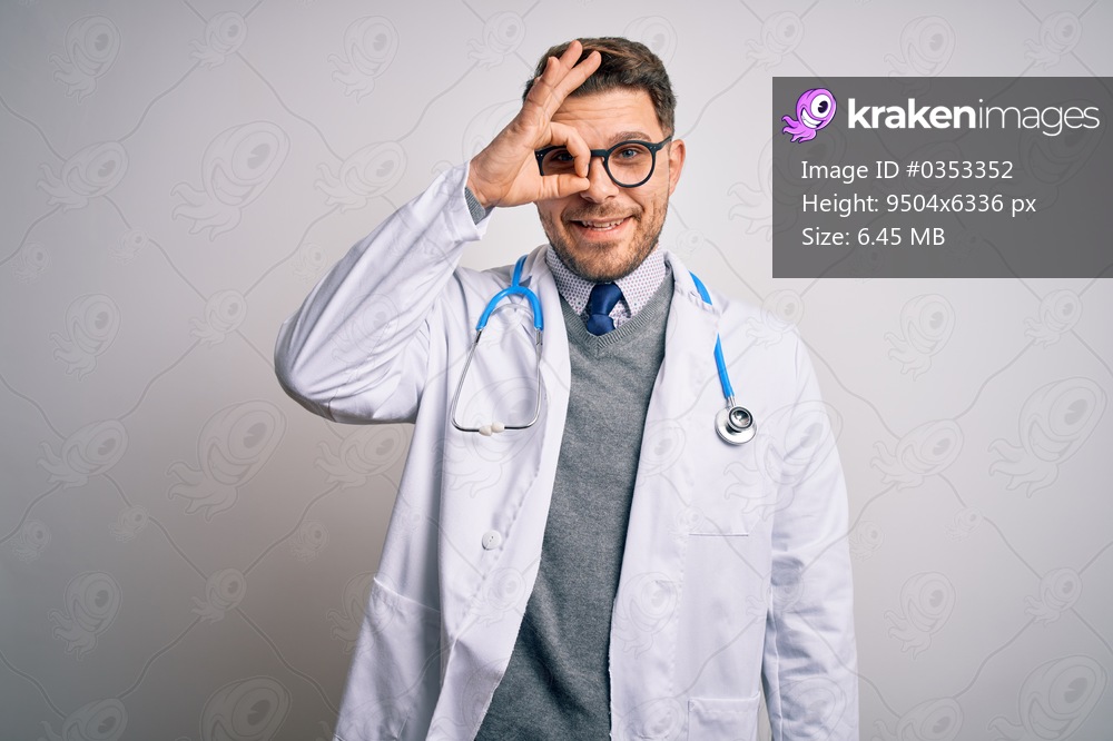 Young doctor man with blue eyes wearing medical coat and stethoscope over isolated background doing ok gesture with hand smiling, eye looking through fingers with happy face.