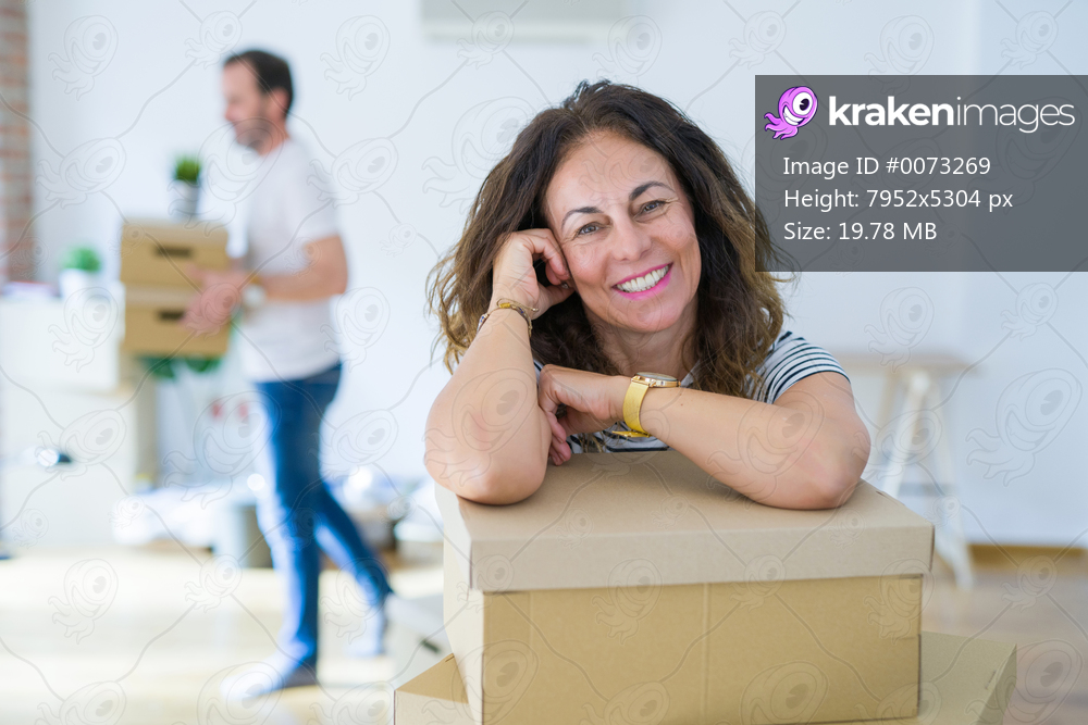 Middle age senior couple moving to a new house, woman smiling happy in love with new apartment
