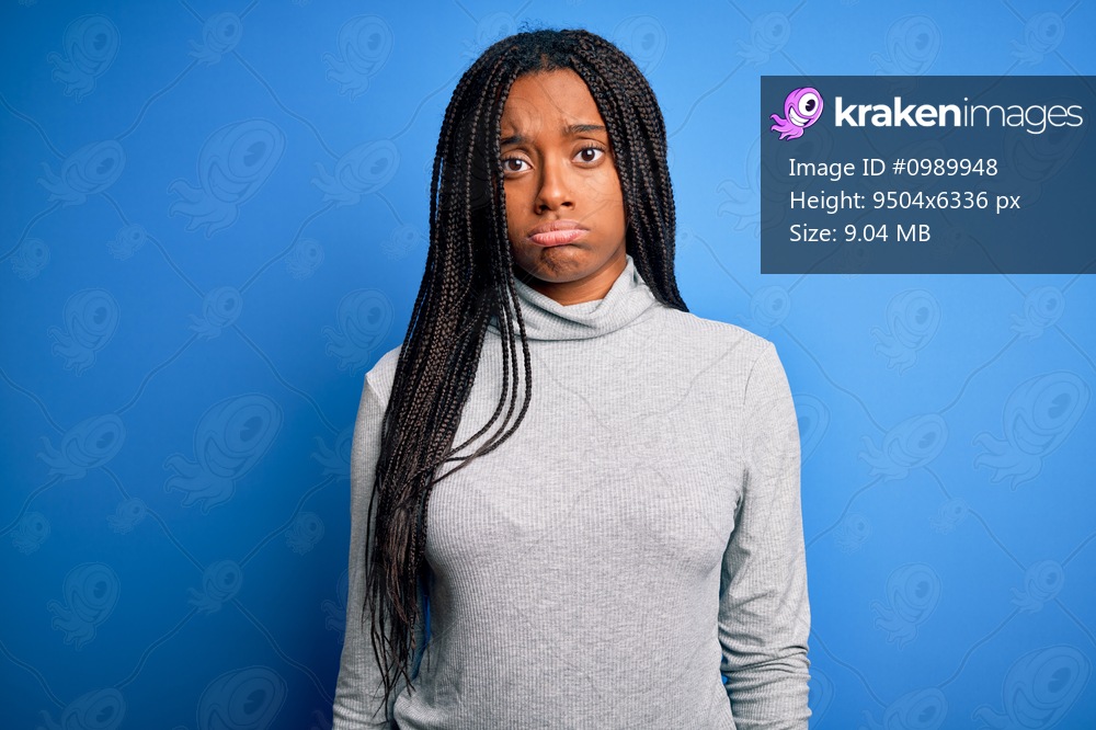 Young african american woman standing wearing casual turtleneck over blue isolated background depressed and worry for distress, crying angry and afraid. Sad expression.