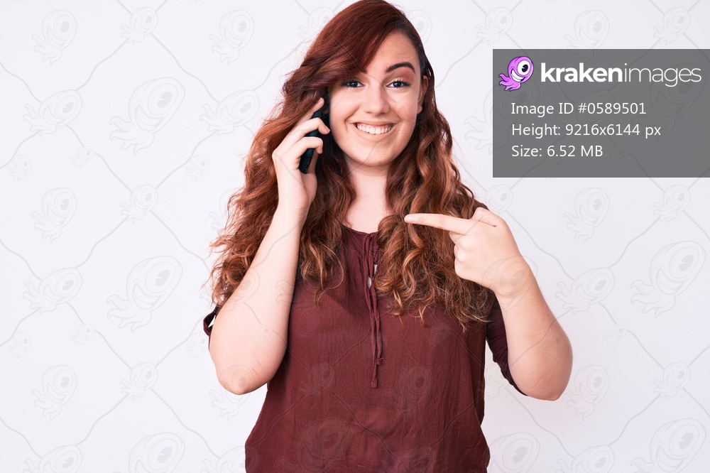 Young beautiful woman having conversation talking on the smartphone pointing finger to one self smiling happy and proud 