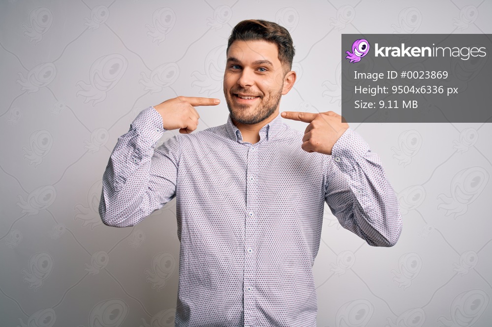 Young business man with blue eyes standing over isolated background smiling cheerful showing and pointing with fingers teeth and mouth. Dental health concept.