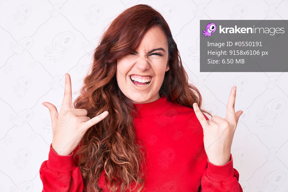 Young beautiful woman wearing casual clothes shouting with crazy expression doing rock symbol with hands up. music star. heavy concept. 