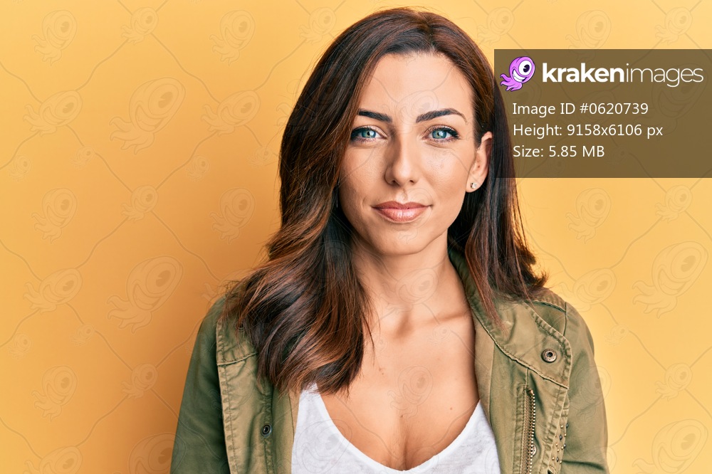 Young brunette woman wearing casual clothes over yellow background relaxed with serious expression on face. simple and natural looking at the camera. 