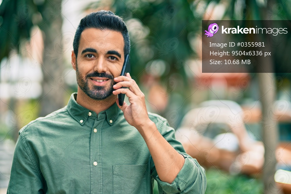 Young hispanic man smiling happy talking on the smartphone at the city.