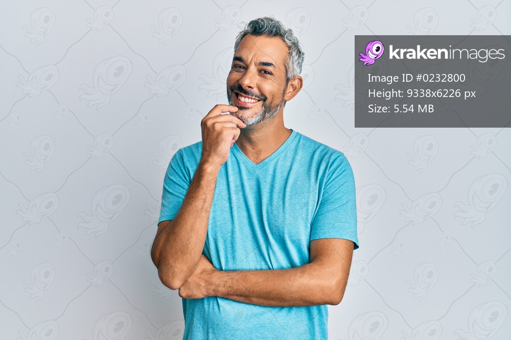 Middle age grey-haired man wearing casual clothes looking confident at the camera with smile with crossed arms and hand raised on chin. thinking positive. 